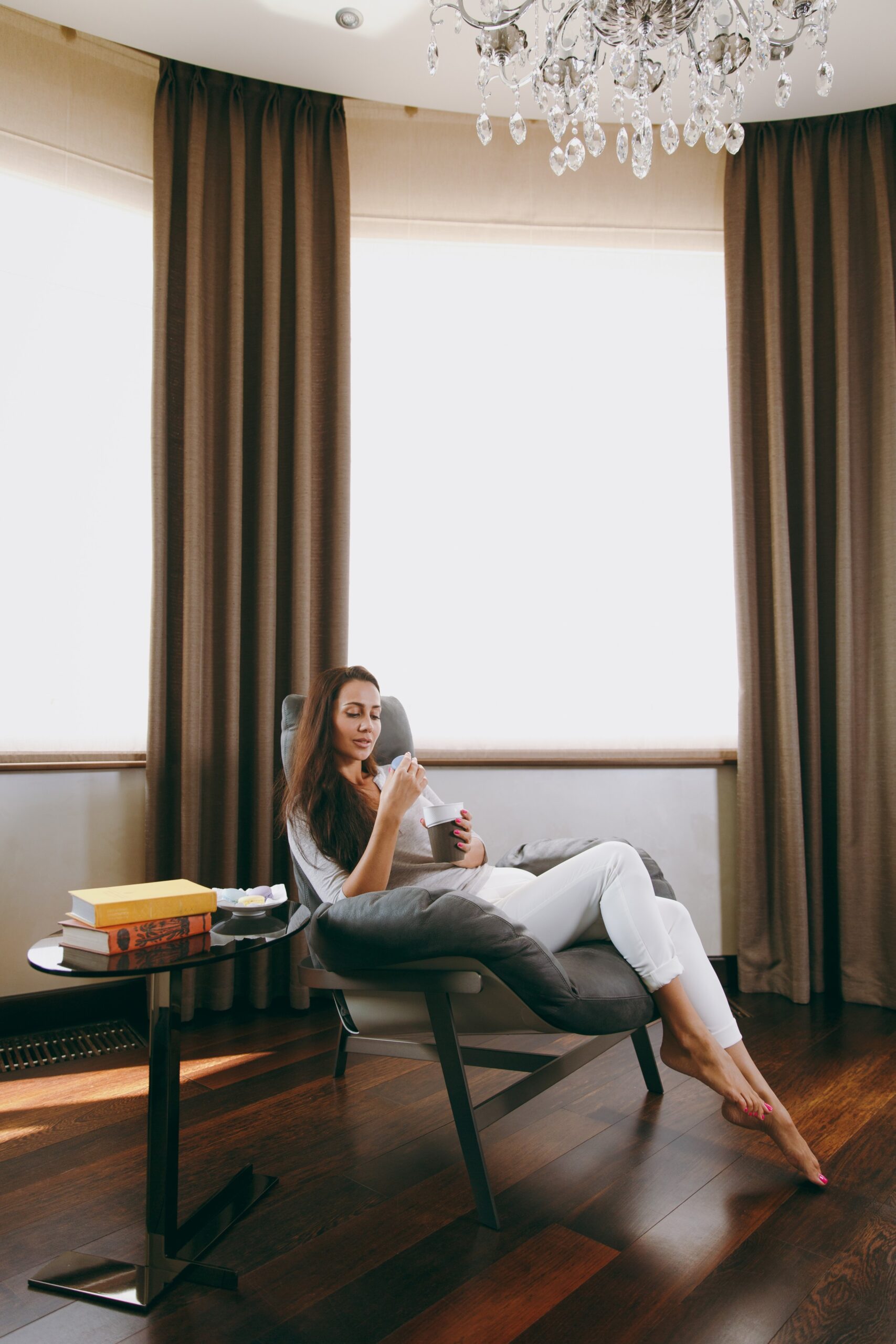 beautiful-young-woman-home-sitting-modern-chair-front-window-relaxing-her-living-room-drinking-coffee-tea (1)