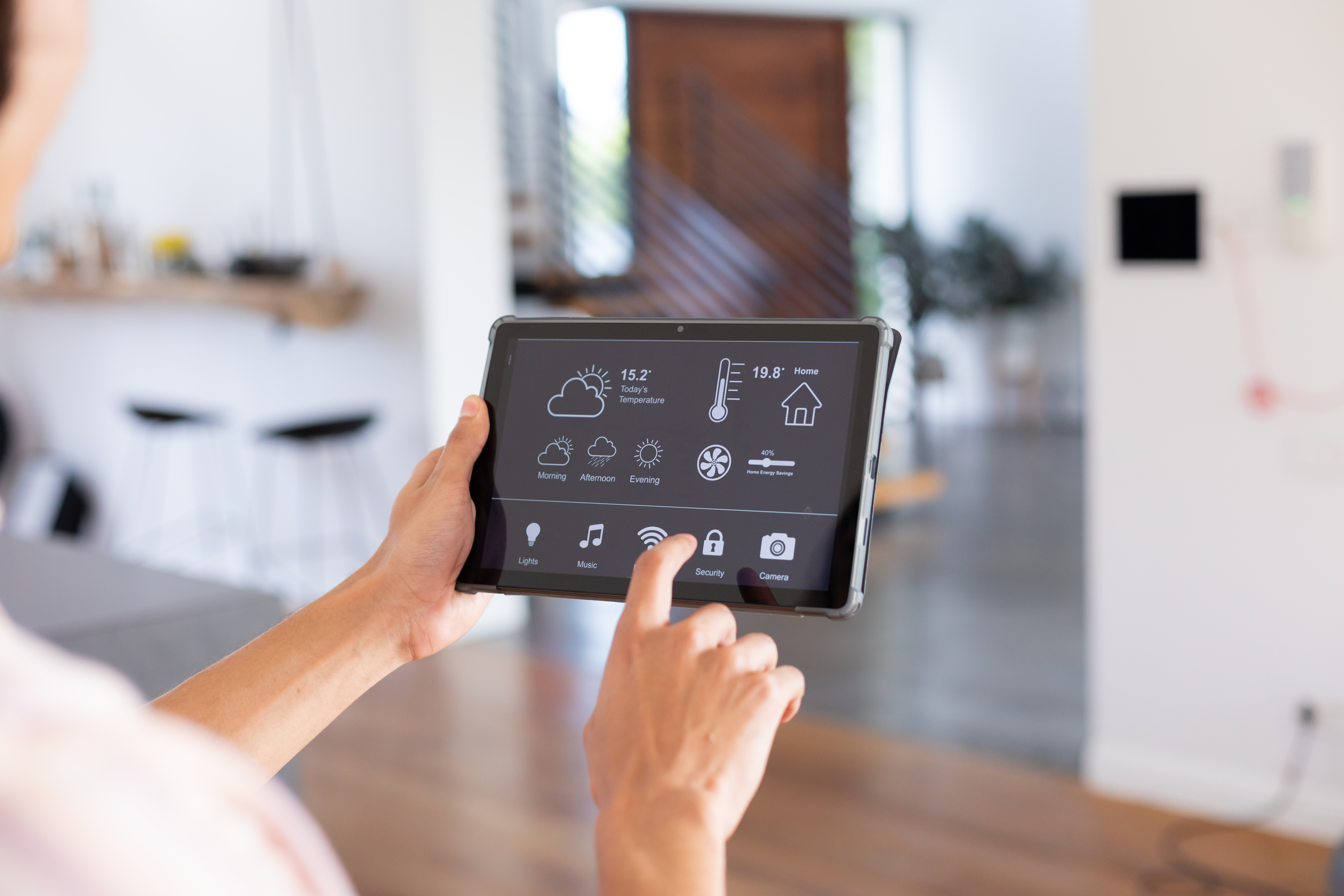 Hands of biracial man at home using tablet with smart home interface on screen. Communication, technology and domestic life concept.
